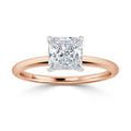 A rose gold ring with a square-cut diamond solitaire in a four-prong white gold setting, on a plain band.