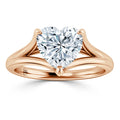 A rose gold ring with a split shank band features a heart-shaped diamond solitaire at the center.