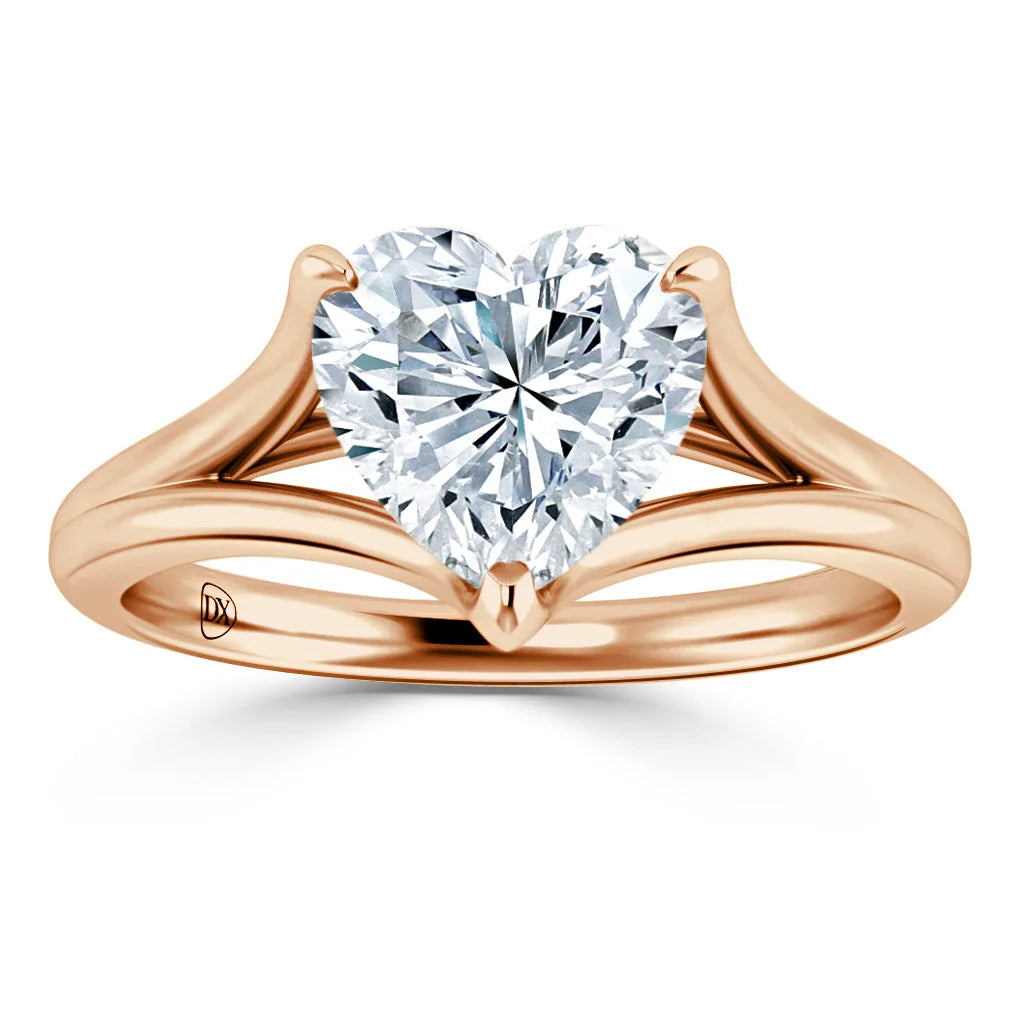 A rose gold ring with a split shank band features a heart-shaped diamond solitaire at the center.