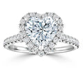 Heart-shaped diamond ring with halo of smaller diamonds on a diamond-studded white gold band, white background.