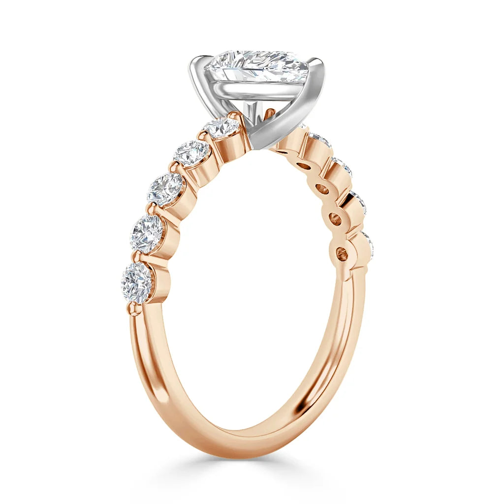Rose gold ring with round diamonds on the band and a marquise-cut diamond in a white gold prong setting.