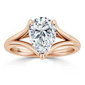 Pear-shaped diamond solitaire ring with a split rose gold band on a white background.