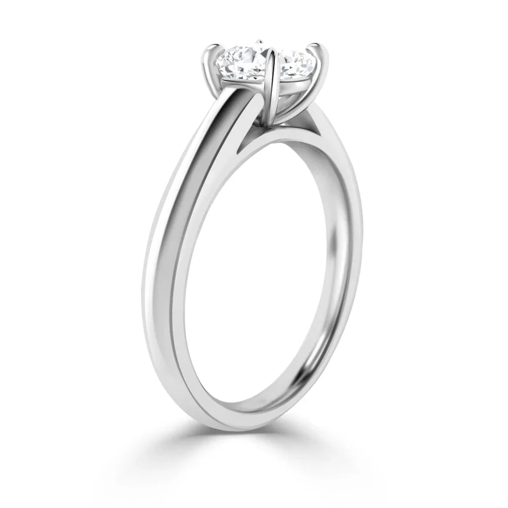 A solitaire engagement ring with a round diamond set in a four-prong white gold band, viewed from the side.