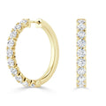 Gold hoop earrings with a row of round, white diamonds set along the front outer edge.
