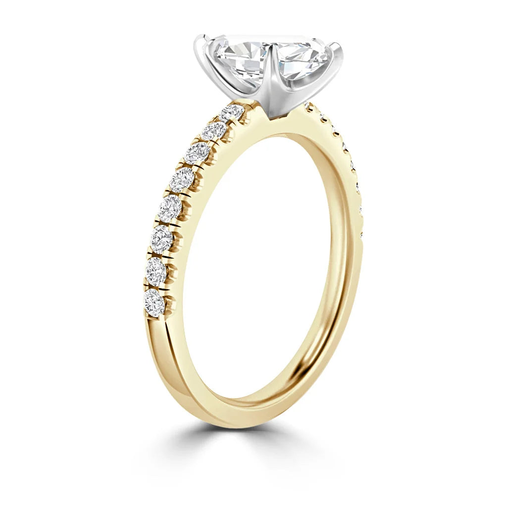 A gold ring with a large center diamond and smaller diamonds set along the band, viewed from the side.