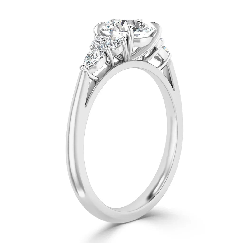 A white gold ring with a round center diamond and two smaller side diamonds in a prong setting.