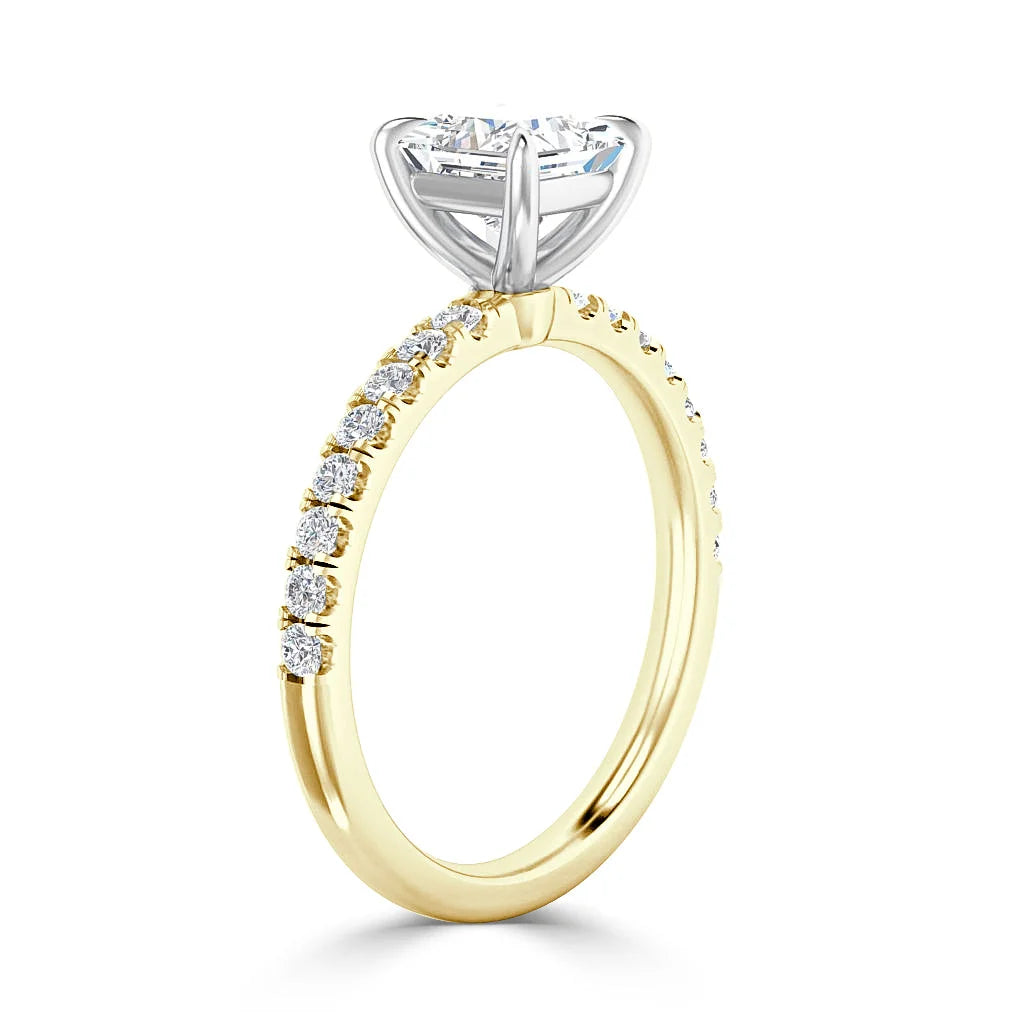 A gold ring with side diamonds and a large round diamond set in a white gold prong setting.