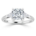 Platinum ring with a cushion-cut center diamond and two triangular diamonds on each side, on a polished band.