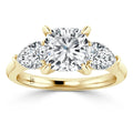 Gold ring with three white diamonds: a large round center stone and two smaller, half-moon diamonds on each side.