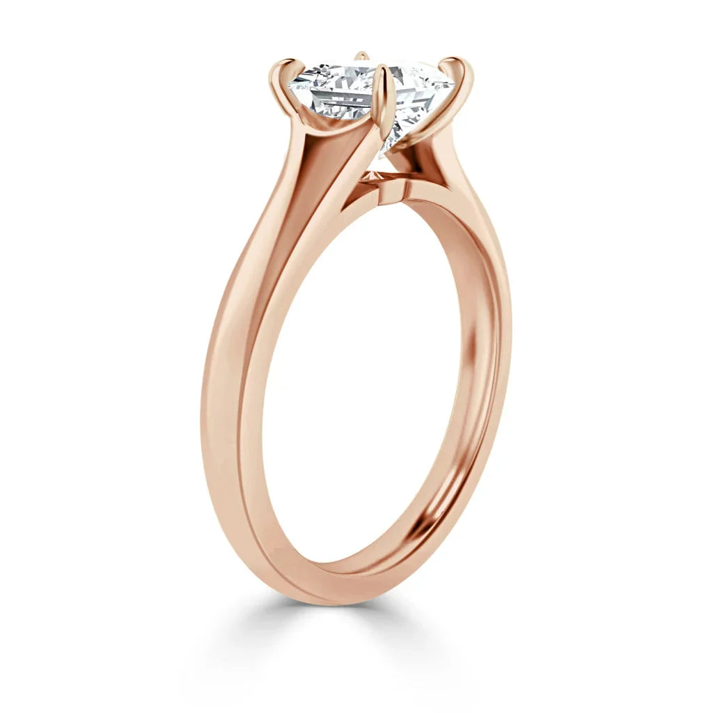Rose gold solitaire ring with a round-cut diamond in a prong setting, shown from a side angle.