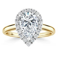A pear-shaped diamond ring with a halo of small diamonds on a yellow gold band, shown against a white background.