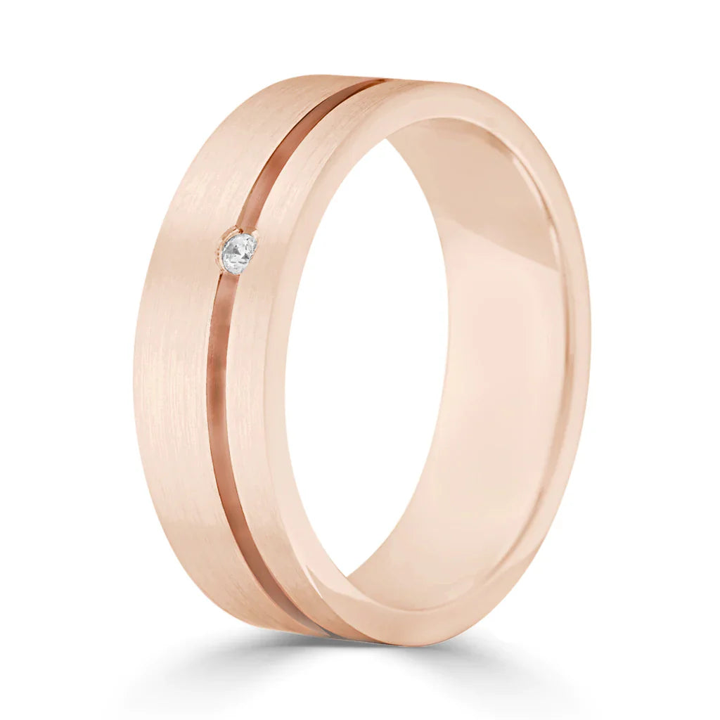Rose gold ring with a single small diamond and a sleek, off-center groove, on a white background.