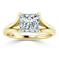 A gold ring with a split shank design, featuring a large princess-cut diamond in a four-prong setting.
