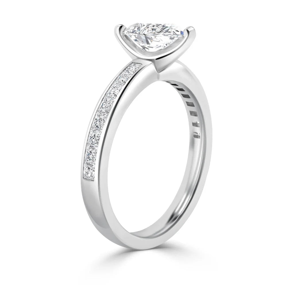 A white gold ring with a pear-cut diamond and small diamonds set along the band’s upper half.