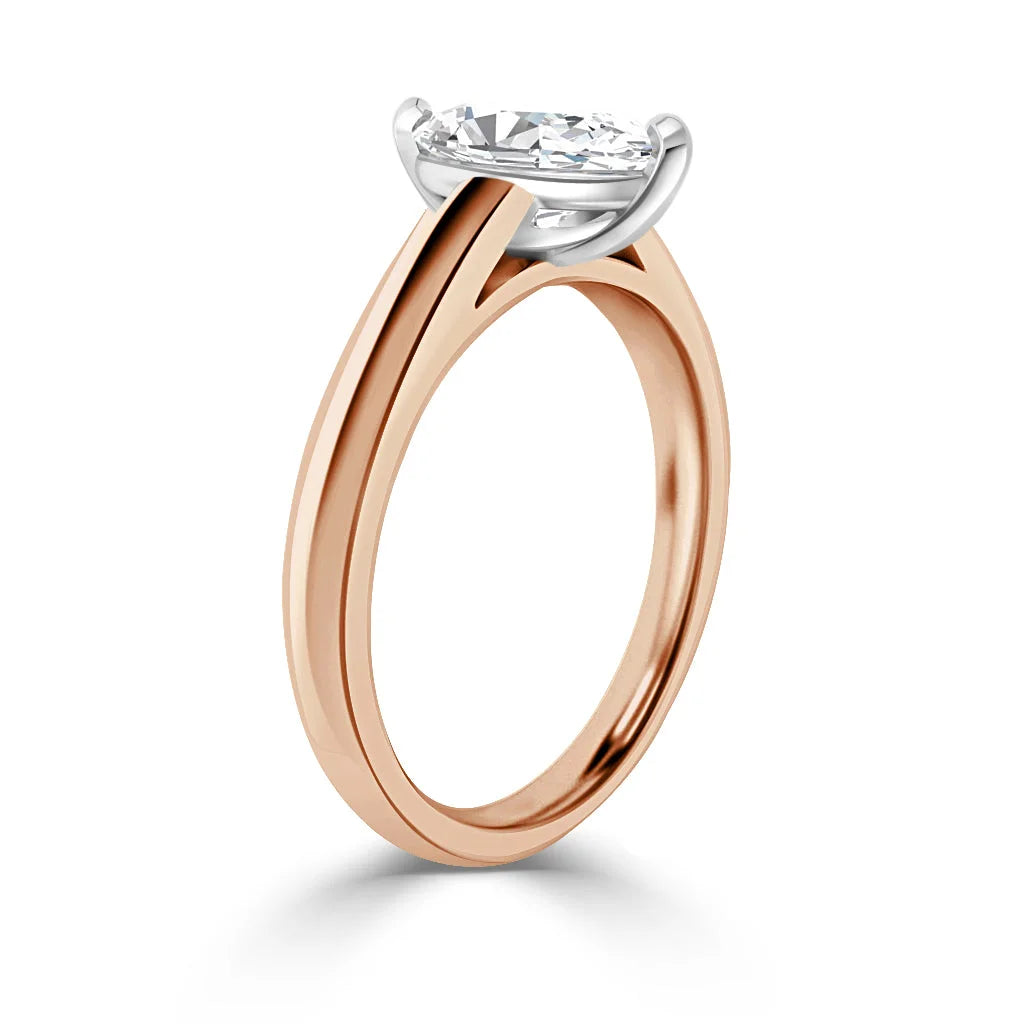 A rose gold ring with a round, white diamond solitaire in a four-prong white gold setting on a plain band.