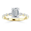 Gold ring with an emerald-cut center diamond and marquise side stones set in a twisted band design.