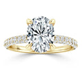 An oval-cut diamond ring with a gold band, featuring small diamonds along the band and four prongs.