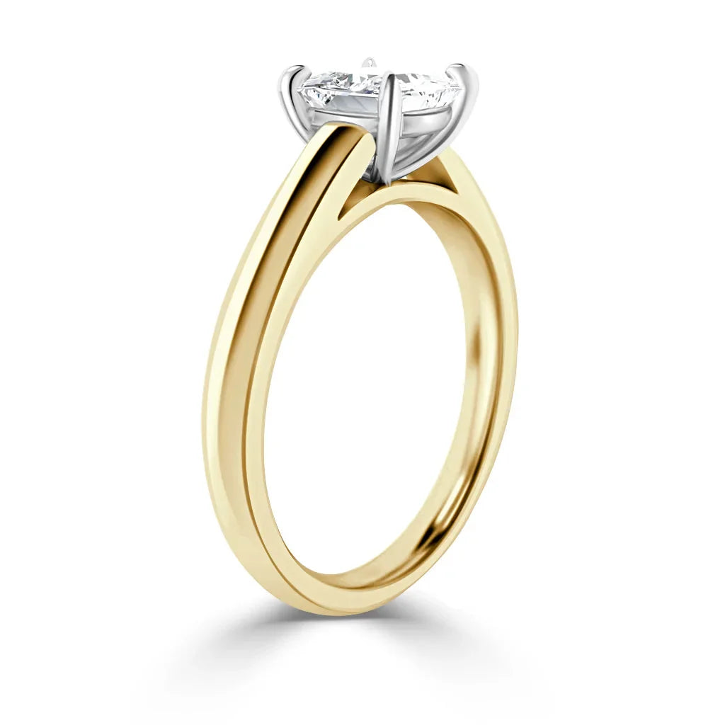 A gold ring with a round, prong-set diamond solitaire in a white gold setting, shown on a white background.