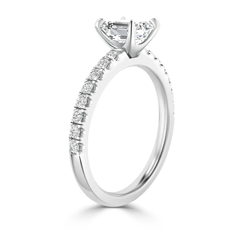 White gold ring with a round solitaire diamond and smaller diamonds along the band, shown from a side angle.
