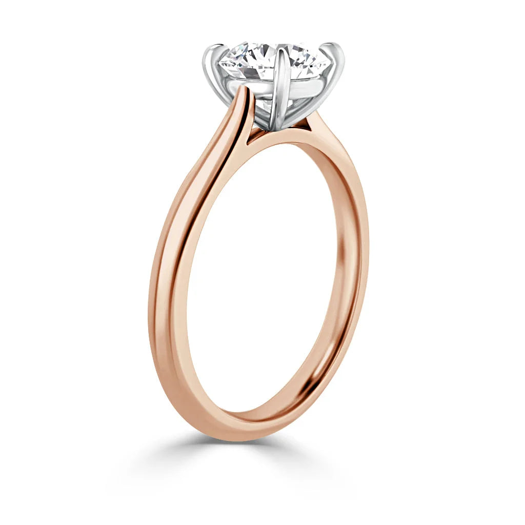 Rose gold ring with a round solitaire diamond held in a six-prong white gold setting, shown from the side.