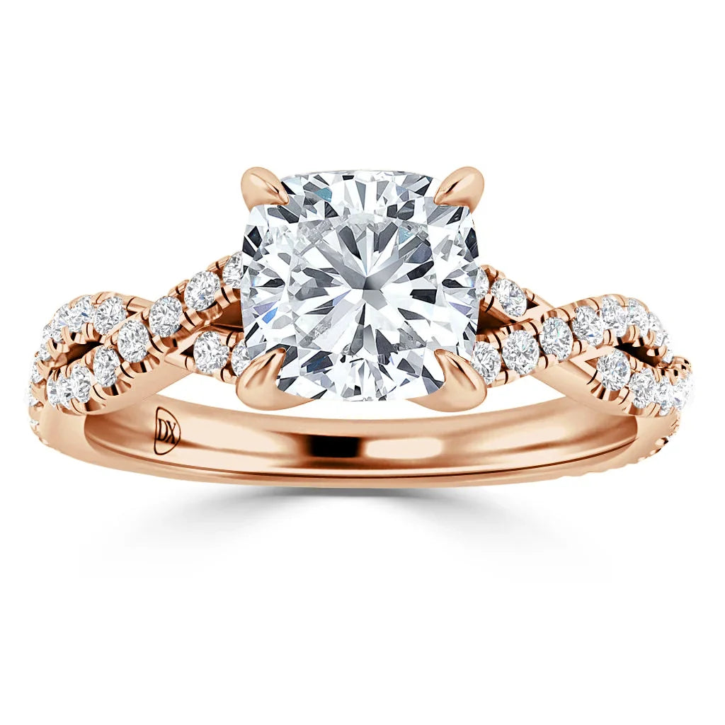 A rose gold ring with a cushion-cut center diamond and a twisted, diamond-accented band.