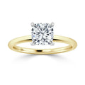 A gold ring with a cushion-cut diamond solitaire set in a four-prong white gold or platinum setting.