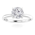 A round-cut diamond solitaire ring with a thin, shiny white metal band and four prongs holding the diamond.