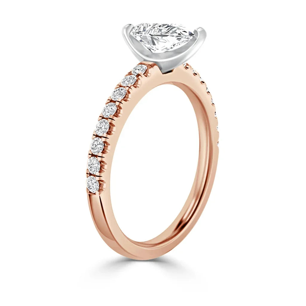 Rose gold ring with oval diamond solitaire and small diamonds set along the upper half of the band.