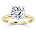 Gold band ring with a large round diamond solitaire in a four-prong white metal setting, on a white background.