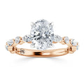 Oval diamond ring with twisted rose gold band and side diamonds, viewed from the front on a white background.
