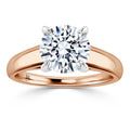A round diamond solitaire ring with a rose gold band and four prongs holding the diamond.