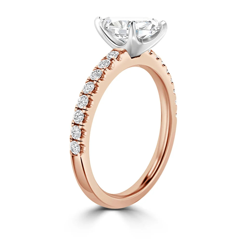 Rose gold ring with side diamonds and a large, round center diamond in a white gold prong setting.
