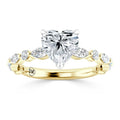 A gold ring with a heart-shaped diamond center and marquise side stones in a twisted band design.
