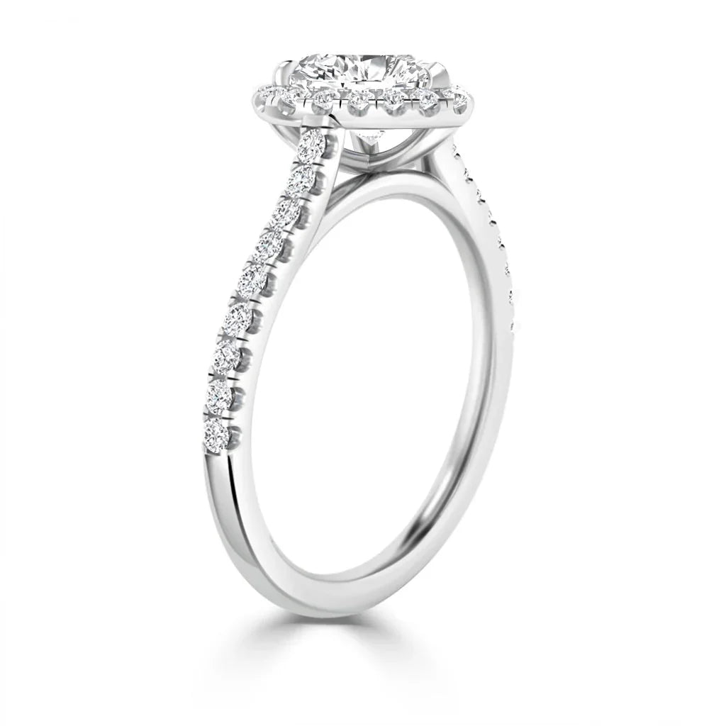 White gold ring with small diamonds along the band and a large round center diamond in a halo setting.