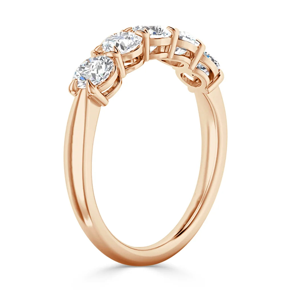 Rose gold ring set with three round, sparkling diamonds in prong settings, viewed from a side angle.