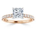Rose gold ring with a princess-cut diamond center and diamonds along the band, viewed from the front.
