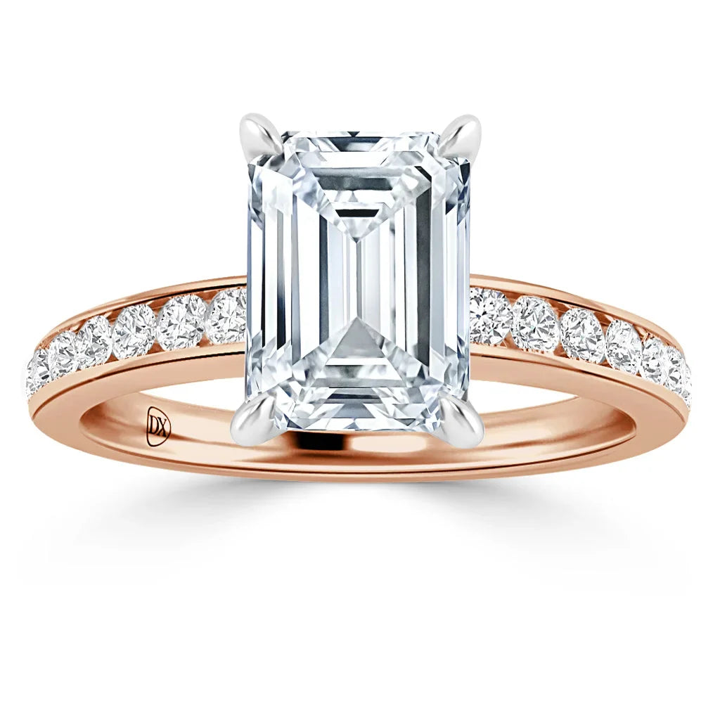 A rose gold ring with an emerald-cut diamond center and small diamonds set along the band.