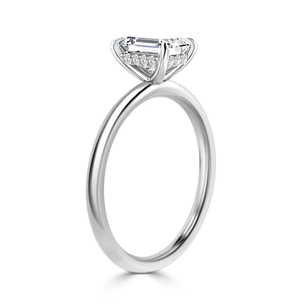 A silver ring with a large rectangular diamond and small diamonds set beneath the main stone on a thin band.