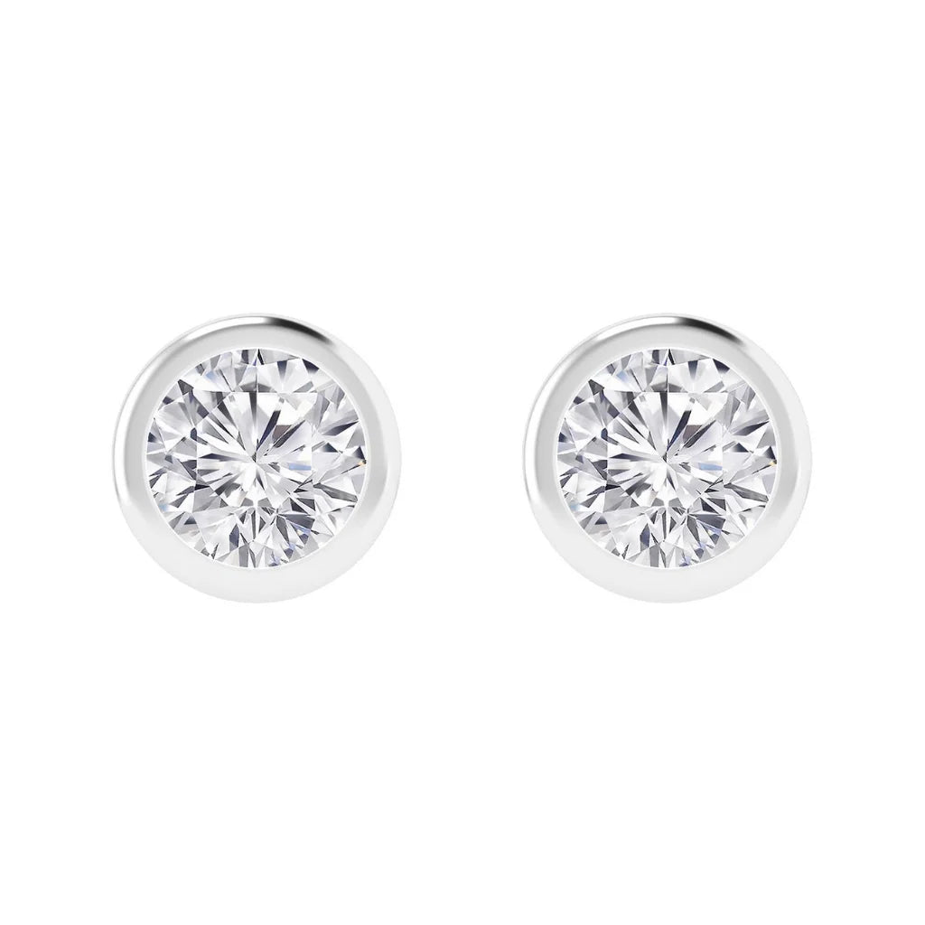 Pair of round, bezel-set diamond stud earrings with a white metal border on a white background.
