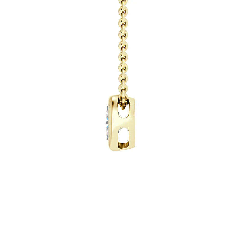 A close-up of a gold chain necklace with a side view of a rectangular pendant holding a clear gemstone.
