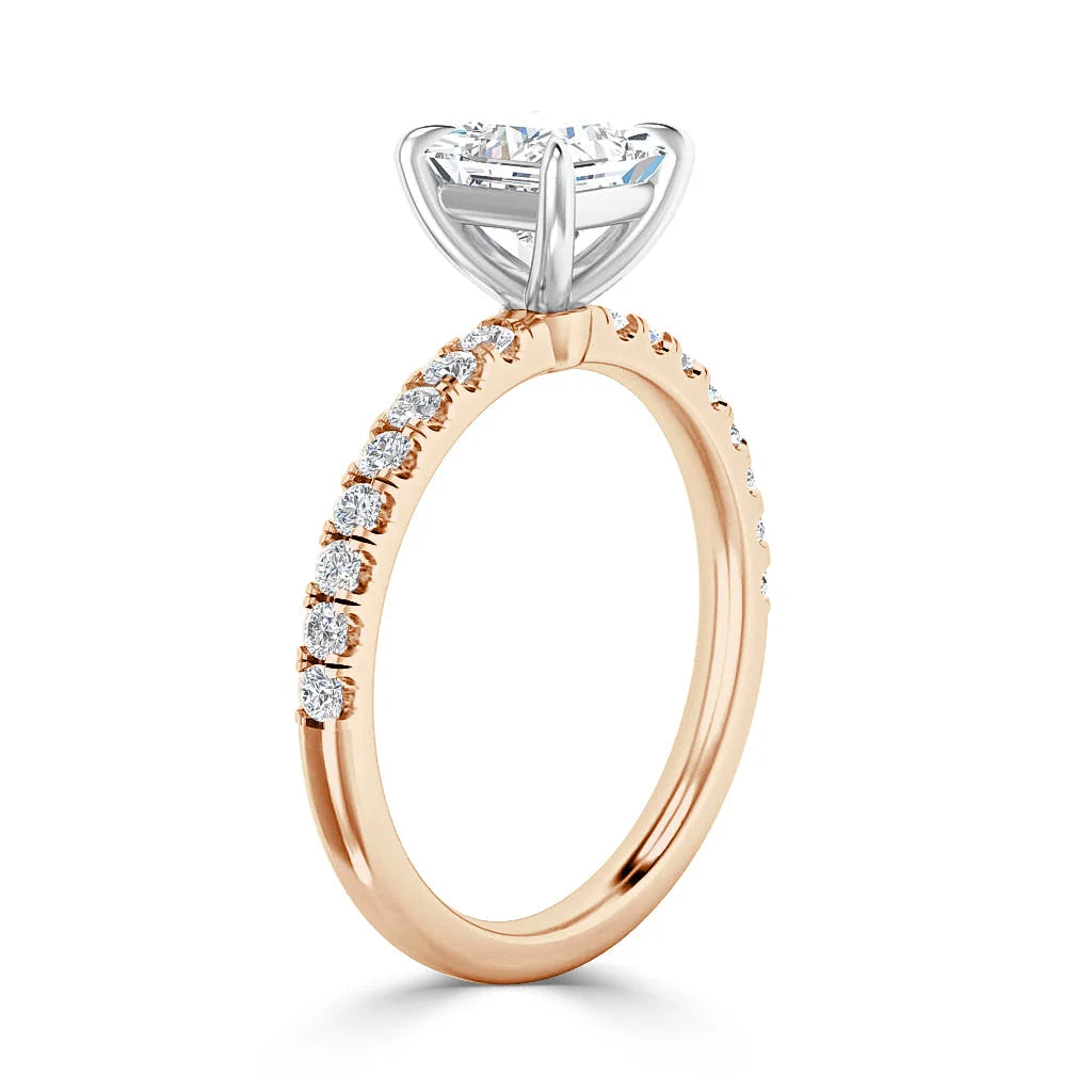 A rose gold ring with small diamonds on the band and a large round diamond in a silver prong setting.