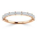 A rose gold ring with seven rectangular baguette-cut diamonds set across the top in a single row.