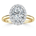 Gold band ring with an oval halo of diamonds surrounding a large oval center diamond, on white background.