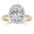 A gold ring with an oval-cut diamond center stone, surrounded by a diamond halo and pavé diamond band.