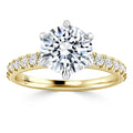 Gold ring with a large round diamond center stone and smaller diamonds set along the band, on a white background.