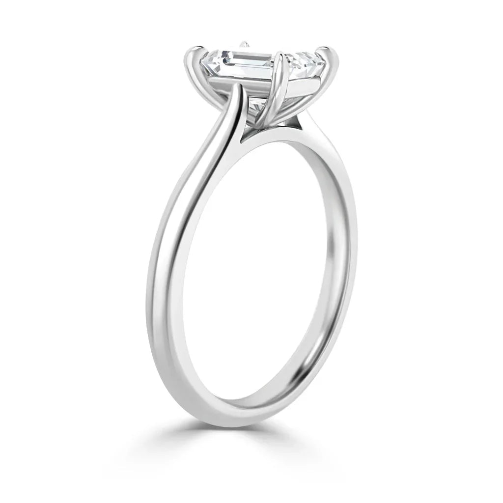 A white gold ring with a round, prong-set solitaire diamond viewed from a side angle on a white background.