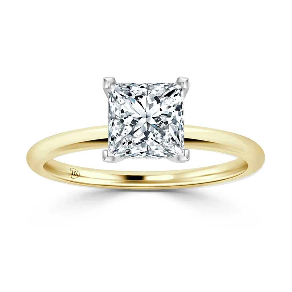 A gold band ring with a large, square-cut diamond solitaire in a four-prong white gold setting.