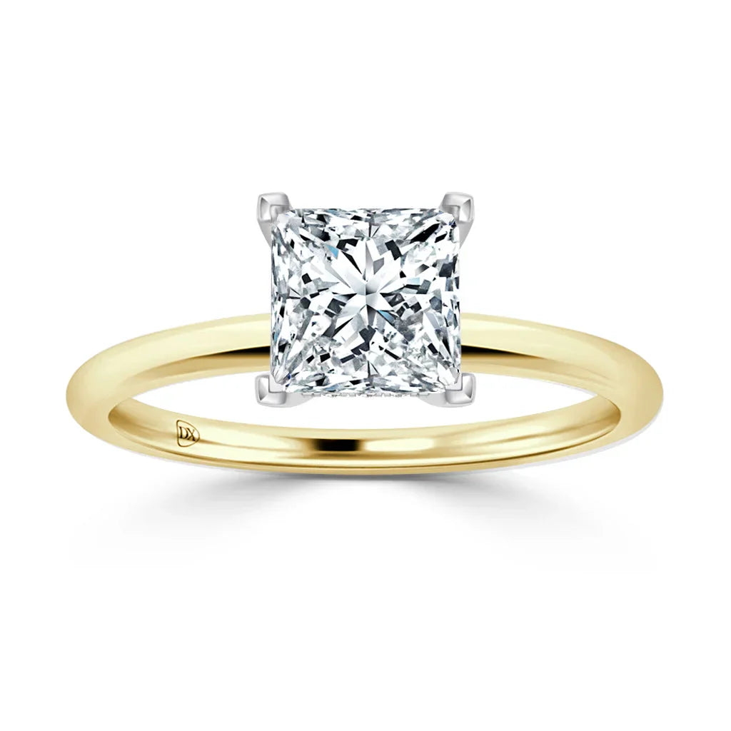 A gold band ring with a large, square-cut diamond solitaire in a four-prong white gold setting.