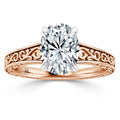 Rose gold ring with ornate filigree band and large oval diamond centerpiece set in four prongs.