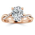 A rose gold ring with an oval diamond center and a twisted band adorned with smaller round diamonds.